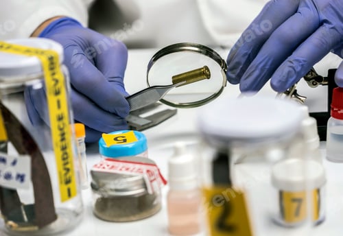 Preview: Expert police examines a bullet cap in scientific laboratory with magnifying glass