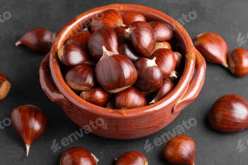 Preview: Fresh chestnuts in a clay bowl on black background