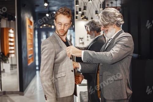 Preview: Senior man choosing a new suit in a store