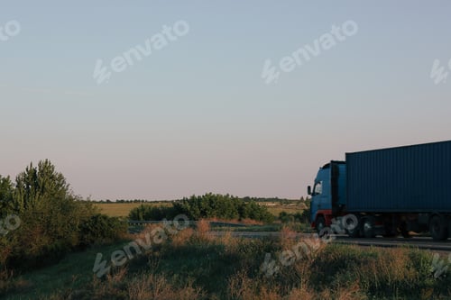 Preview: Truck is driving on the highway among the fields on blue sky background
