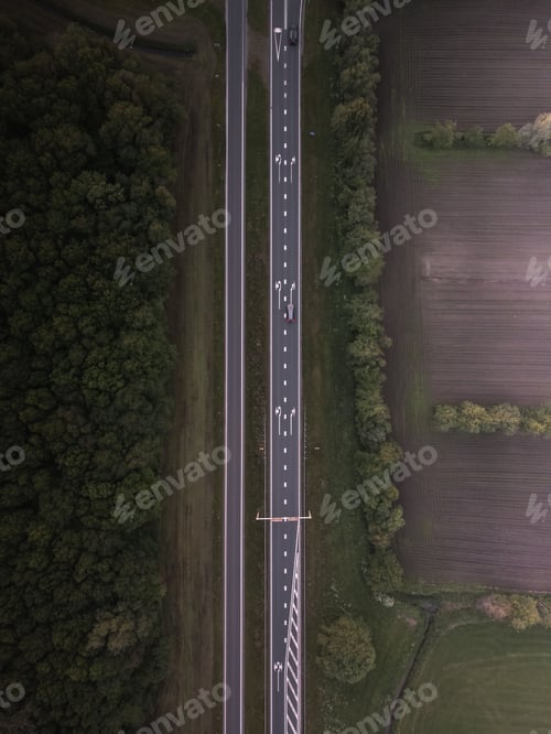 Preview: Top-down drone shot of a road with forest on one side.