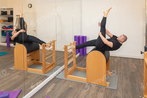 Preview: Male fitness Pilates trainer shows exercises on special simulators. Pilates Stretch Tables