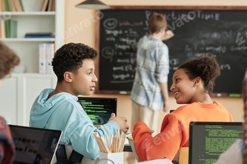 Preview: Side view two teenagers taking in programming class for children