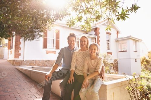 Preview: A place to call home. A portrait of a happy family sitting outside of their home.