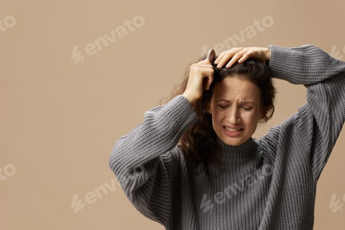 Preview: Problematic unruly damaged hair concept. Tormented curly beautiful woman in gray casual sweater with