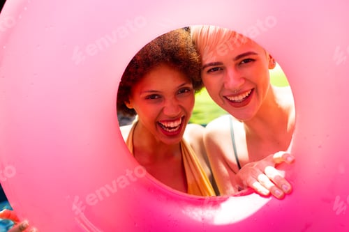 Preview: Portrait of happy diverse female friends having pool party, holding swim ring and smiling in garden
