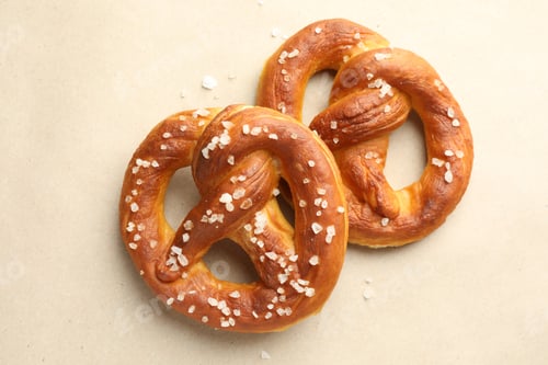 Preview: Tasty pretzels with salt on beige background, flat lay
