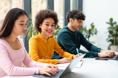 Preview: Happy black female student studying in classroom group, writing essay or preparing for test