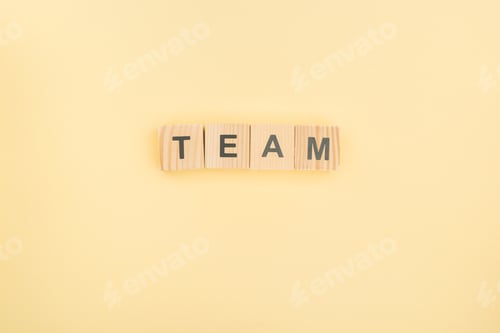 Preview: top view of team lettering made of wooden cubes on yellow background