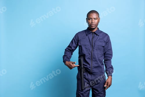 Preview: Male security guard pointing to his baton to ensure protection on duty