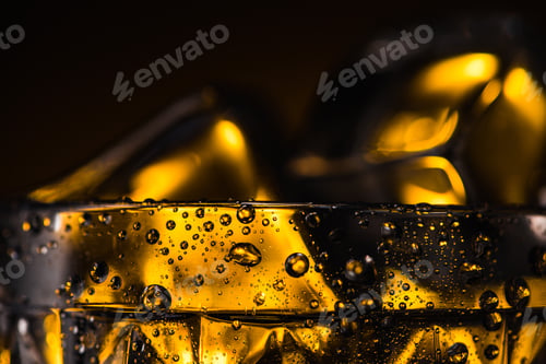 Preview: Close up View of Geometric Faceted Glass With Yellow Illumination in Dark