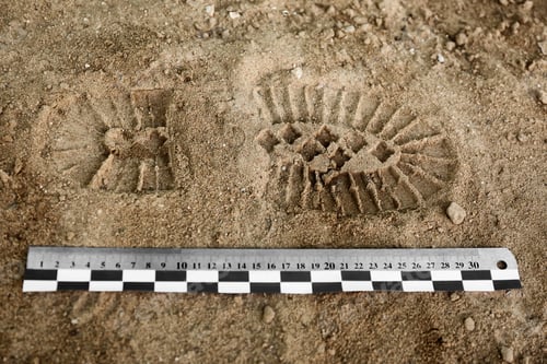 Preview: Ruler near footprint on sand, top view. Crime scene investigation and detective work