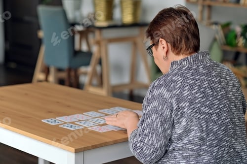 Preview: senior woman playing solitaire at home. Happy old lady plays an intellectual game