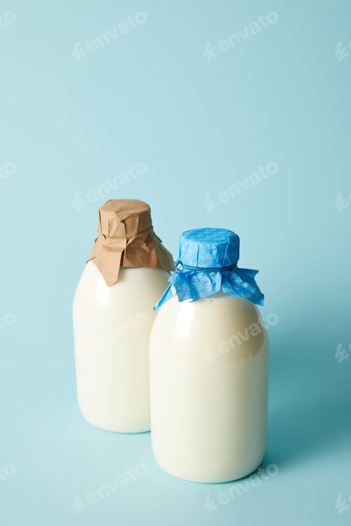 Preview: two fresh milk bottles wrapped by paper on blue background