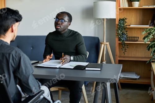 Preview: Young African American HR manager interviewing Hispanic man with disability in wheelchair