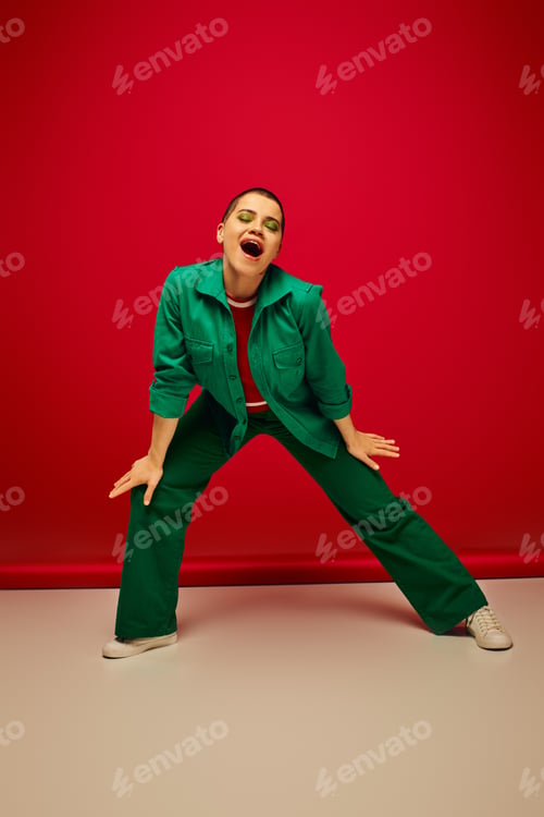 Preview: fashion statement, vibrant backdrop, young woman in stylish attire posing with opened mouth on red