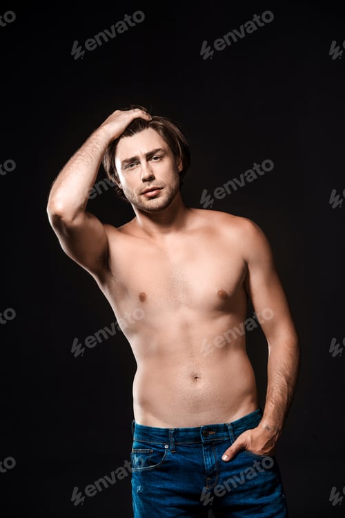 Preview: portrait of handsome shirtless man in jeans looking at camera isolated on black