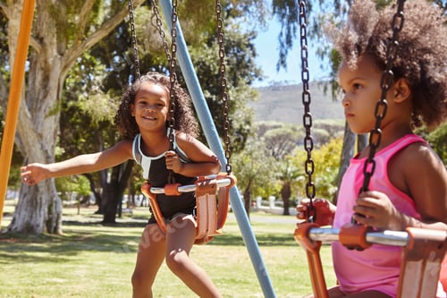 Preview: Two young sisters playing on park swings