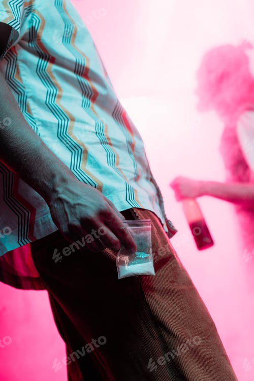 Preview: partial view of man holding in hand drugs in plastic zipper bag in nightclub