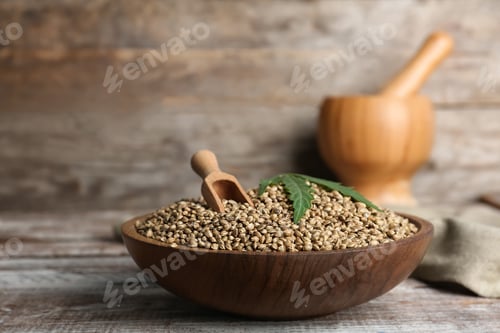 Preview: Bowl of hemp seeds on table against wooden wall