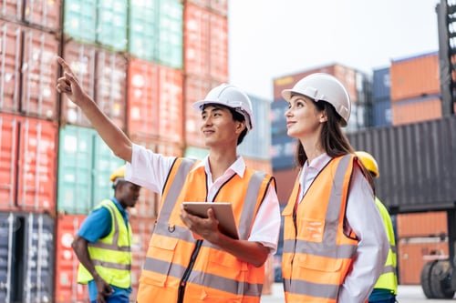 Preview: Caucasian business woman and Asian man working in container terminal.