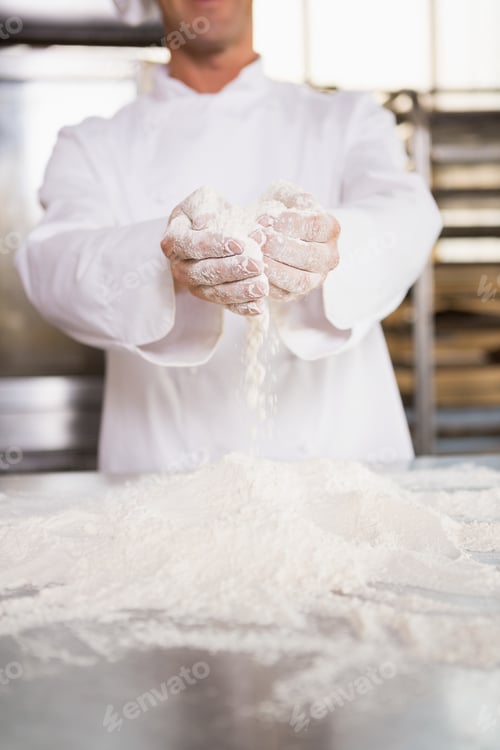 Preview: Close up of bakers hands holding flour in the kitchen of the bakery