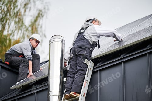 Preview: Technicians installing photovoltaic solar panels on roof of house.