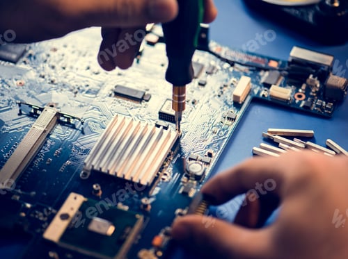 Preview: Closeup of hands with screwdriver over computer mainboard