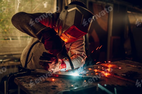 Preview: Man worker welding metal with welding machine in a factory or workshop