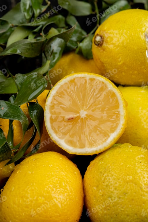 Preview: side view of fresh ripe lemons with water drops and green leaves on black background