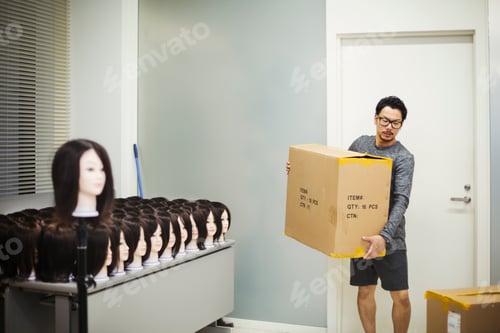 Preview: Man carrying a box in a wig shop