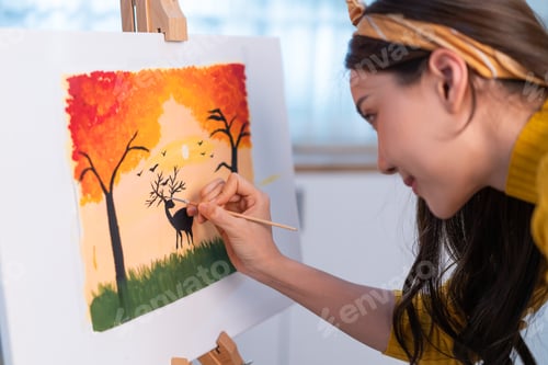 Preview: Asian young talented woman artist coloring on painting board in house.