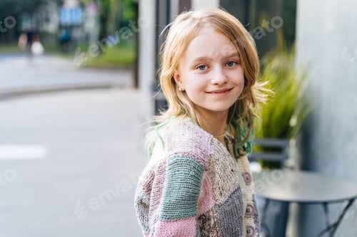 Preview: A young girl is smiling and wearing a multicolored sweater.