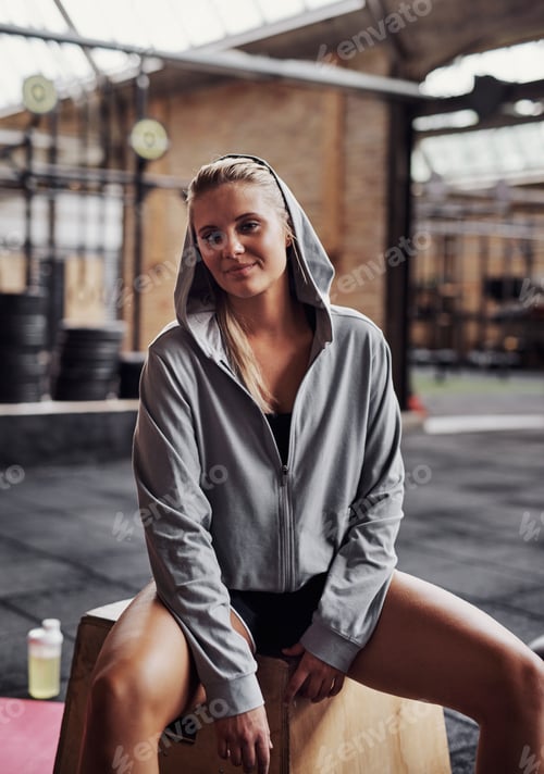Preview: Smiling young woman sitting in a gym after working out