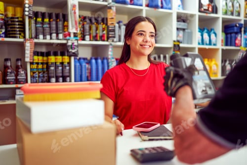 Preview: Smiling saleswoman assisting customer making purchase at auto parts store