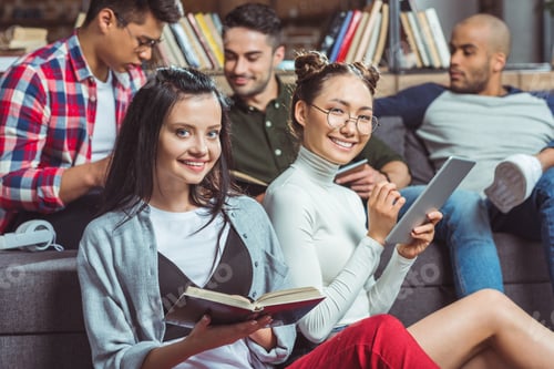 Preview: happy multiethnic students studying together and smiling at camera