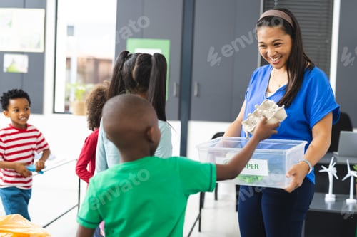 Preview: In school, middle-aged biracial teacher is showing recycling to diverse students