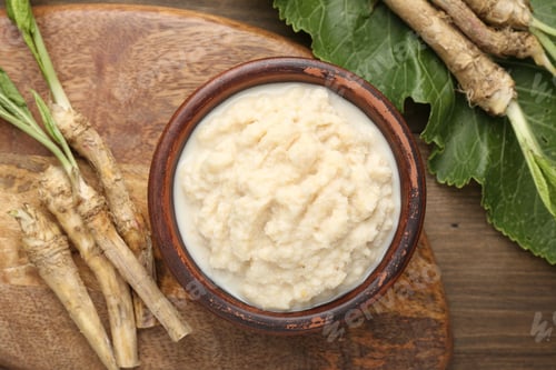 Preview: Tasty horseradish sauce and roots on wooden table, flat lay