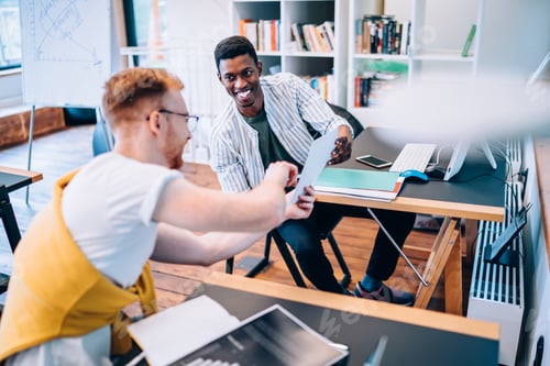 Preview: Cheerful black man helping colleague with data