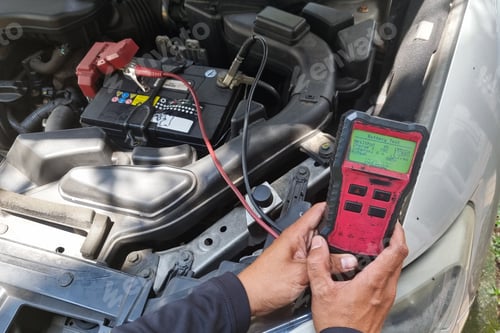 Preview: Technician diagnosing old battery health of automobile with instrument. Test result suggested