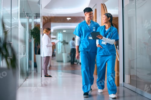 Preview: Male And Female Doctors Or Nurses In Scrubs With Digital Tablet In Hospital With Colleagues Behind