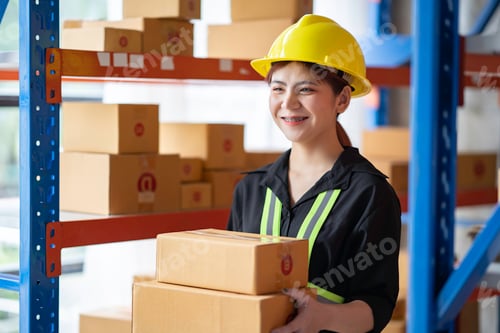 Preview: Portrait of an Asian woman smiling happily and proudly in a warehouse. By holding the parcel box tha