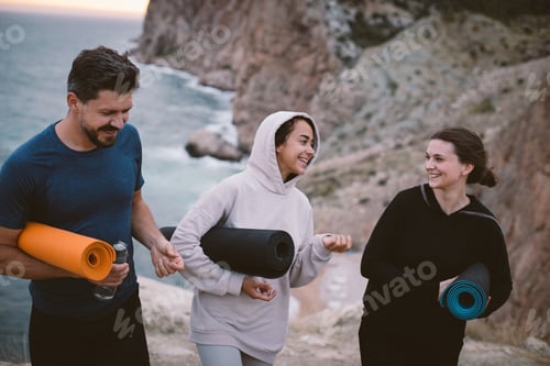 Preview: Group of young people going home from yoga class outdoors with beautiful sea view. Healthy lifestyle