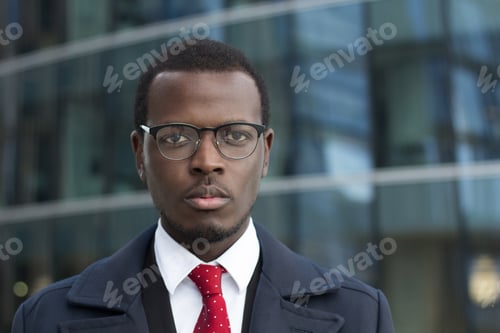Preview: Young handsome African businessman looks at camera with concentrated face