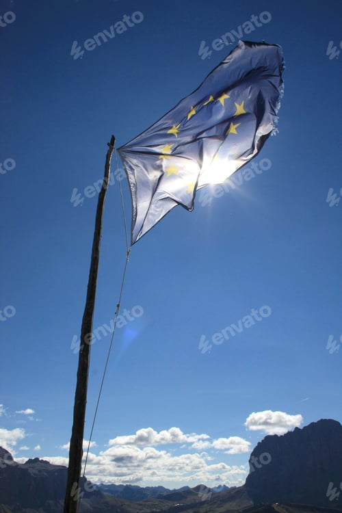 Preview: EU flag in front of blue sky with sunshine - europe flag on wind lighted by sun