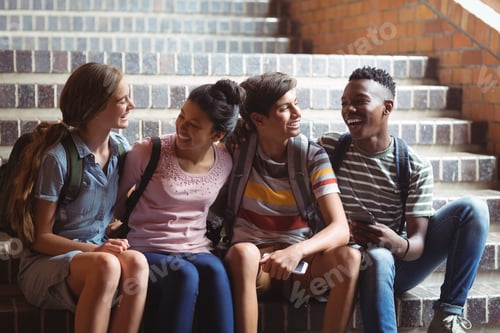 Preview: Happy classmates sitting on staircase