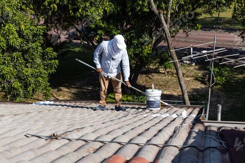Preview: Painter worker adding undercoat foundation paint onto wall with roller at residential building in