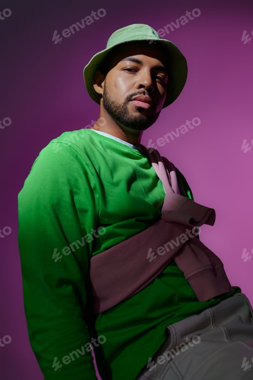 Preview: young handsome man in green panama with purple sweatshirt tied on his shoulders, fashion concept
