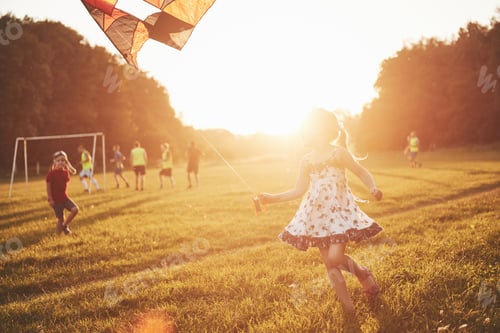 Preview: Cute little girl with long hair running with kite in the field on summer sunny day