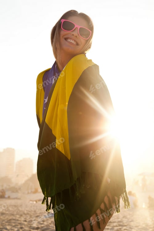 Preview: Young woman wrapped in Brazilian Flag in sunlight